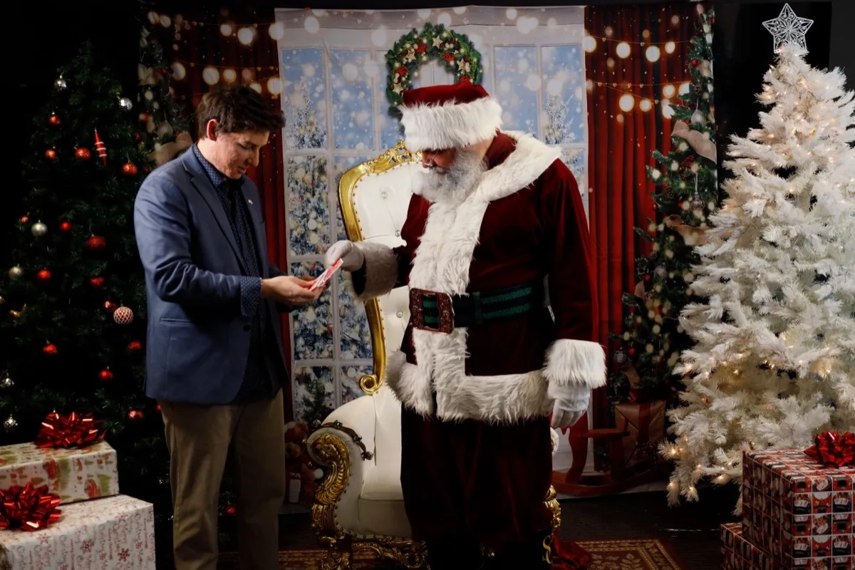 Michael Bloemeke performing holiday magic alongside Santa Claus at a Christmas party