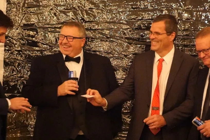 Tuxedo-clad guests laughing during a close-up magic performance by Michael Bloemeke.